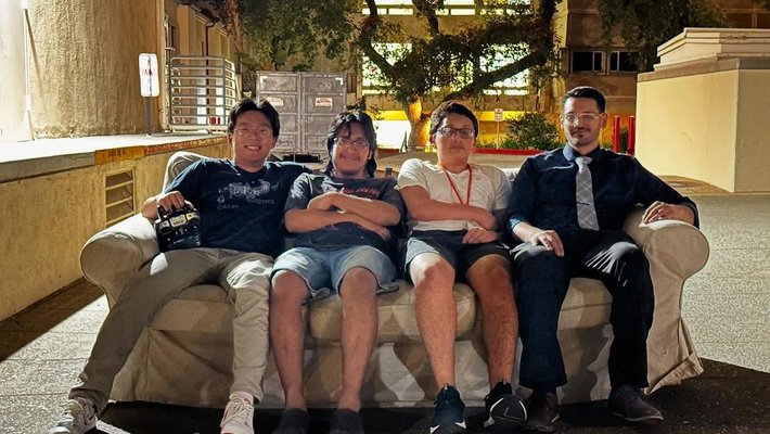 Four Caltech students sitting on a brown couch that they turned into a robot.