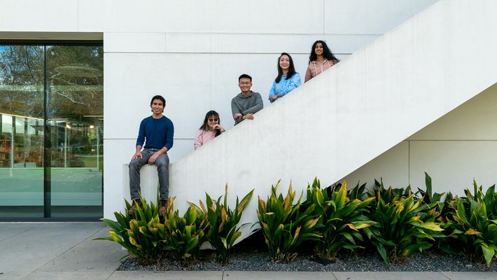 Five students pose on white staircase